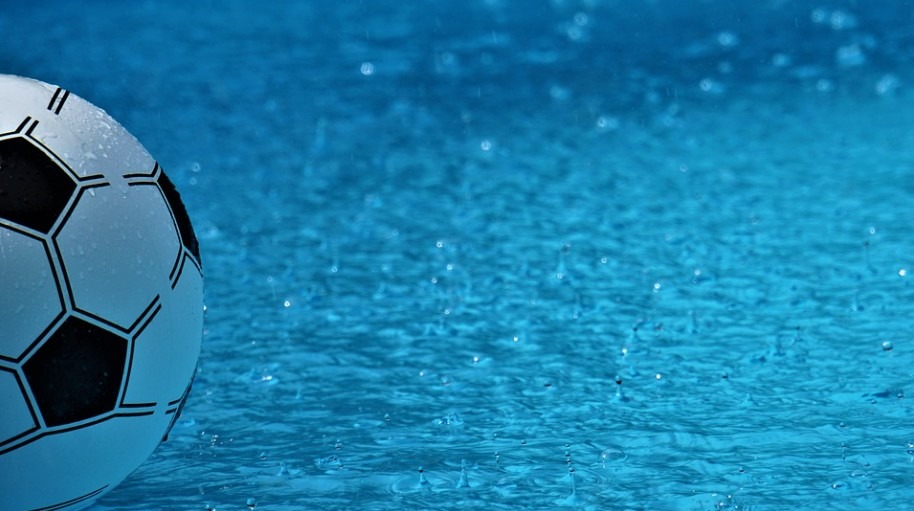 A plastic ball close-up floating on water covered in water drops